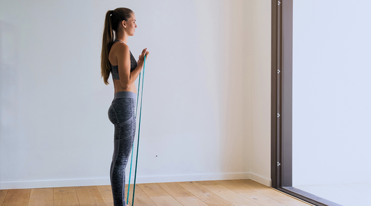 A woman standing holding a resistance band, ready for a workout.